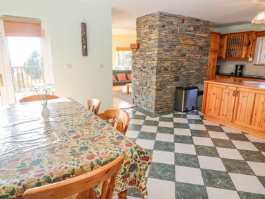 A kitchen and dining area with a checkered floor and a stone wall at Bluebell House and Gardens in Gurteenulla near Ballydehob County Cork