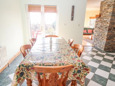 A dining room with a table covered by a floral tablecloth with wooden chairs around it and a vase in the center at Bluebell House and Gardens Gurteenulla near Ballydehob County Cork