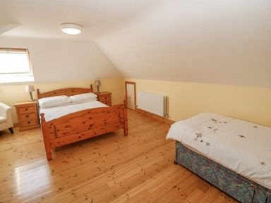 A bedroom with a double wooden bed two bedside tables and a single bed at Bluebell House and Gardens Gurteenulla near Ballydehob County Cork