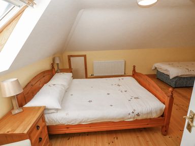 A bedroom with two wooden beds bedside tables with lamps a radiator and a skylight window at Bluebell House and Gardens in Gurteenulla near Ballydehob County Cork
