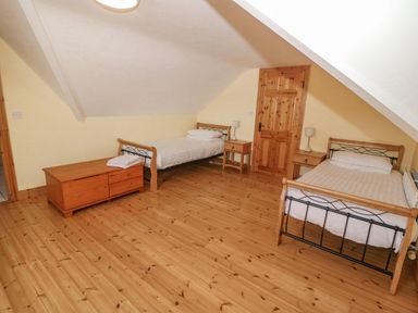 A bedroom with two single beds two nightstands a wooden chest and a wooden door at Bluebell House and Gardens in Gurteenulla near Ballydehob County Cork