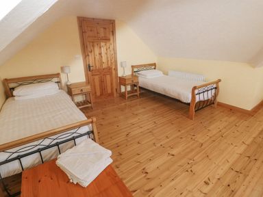 A bedroom with two single beds a wooden door and two bedside tables with lamps at Bluebell House and Gardens Gurteenulla near Ballydehob County Cork