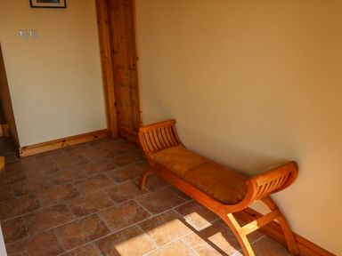 A hallway with a wooden bench with a padded seat and a wooden door at Bluebell House and Gardens in Gurteenulla near Ballydehob County Cork