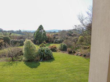 A garden with various trees and shrubs and a grassy lawn at Bluebell House and Gardens in Gurteenulla near Ballydehob County Cork