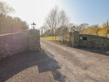 An open gate with stone pillars along a gravel driveway leading to a grassy area with trees at Bluebell House and Gardens Gurteenulla near Ballydehob County Cork