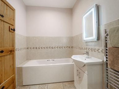 A bathroom with bathtub, sink, and mirror at Briws and 963354 together they sleep 35