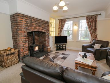 A living room with a brick fireplace leather sofas a wooden coffee table and a television at The Farm House in Bala