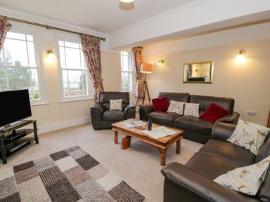 A living room with leather sofas a wooden coffee table a floor lamp and a television at The Farm House in Bala