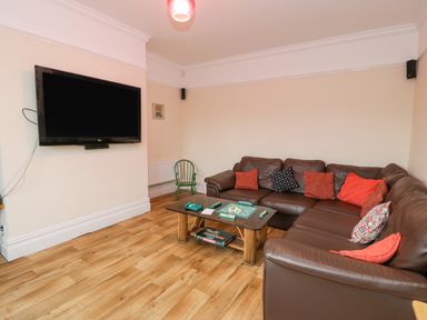A living room with a brown leather sofa and a television on the wall at The Farm House in Bala