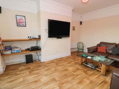 A living room with a wall-mounted television brown leather sofa and a coffee table with a board game at The Farm House in Bala
