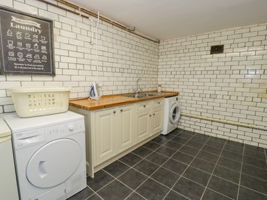 A laundry room with a washing machine dryer sink cabinet and laundry guide on wall at The Farm House in Bala