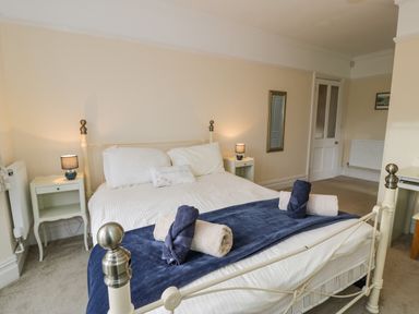 A bedroom with a bed with two rolled towels and bedside tables with lamps at The Farm House in Bala