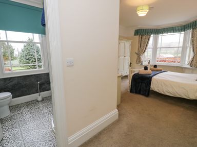 A bedroom with a bed and wardrobe next to a bathroom with a toilet at The Farm House in Bala