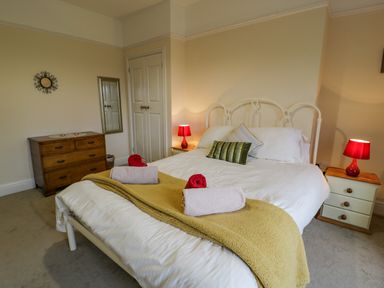 A bedroom with a double bed two bedside tables with lamps a wooden chest of drawers and a wall mirror at The Farm House in Bala