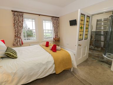 A bedroom with a bed and folded towels near windows and an open door leading to a bathroom at The Farm House in Bala