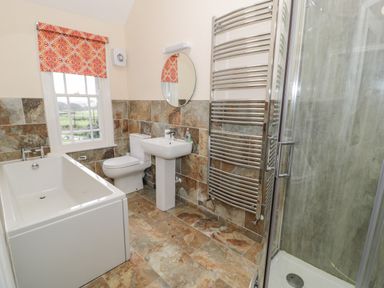 A bathroom with a bathtub toilet sink shower and heated towel rail at The Farm House in Bala