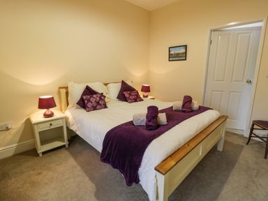 A bedroom with a double bed purple pillows and lamps at The Farm House in Bala