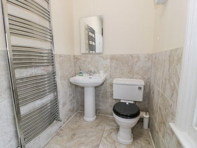 A bathroom with a pedestal sink mirror toilet and towel radiator at The Farm House in Bala