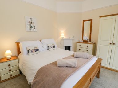 A bedroom with a double bed bedside tables lamps a chest of drawers with a mirror and a wardrobe at The Farm House in Bala