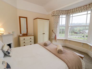 A bedroom with a bed and a dresser next to a wardrobe and a large window at The Farm House in Bala