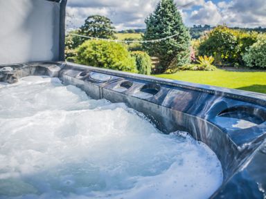 A bubbling hot tub in a garden with grass and trees at The Farm House in Bala