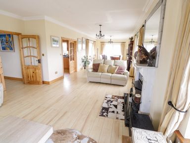 A living room with a white sofa and pillows a fireplace and wooden doors at Shraigh Beach in Belmullet County Mayo