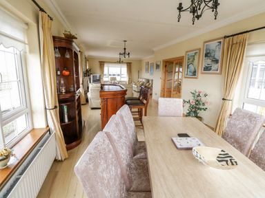 A dining and living room with upholstered chairs a wooden dining table paintings on the wall and a wooden bar at Shraigh Beach in Belmullet County Mayo
