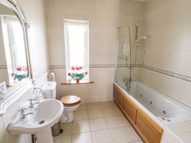 A bathroom with a sink toilet bathtub and a window with flowers at Shraigh Beach in Belmullet County Mayo
