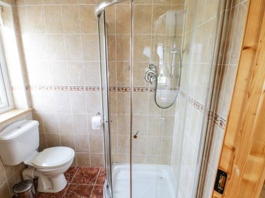 A bathroom with a toilet a glass shower enclosure and tiled walls and floor at Shraigh Beach in Belmullet County Mayo