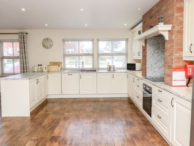 A kitchen with white cabinets a brick oven surround a microwave and appliances at Darling Cottage in Bamburgh