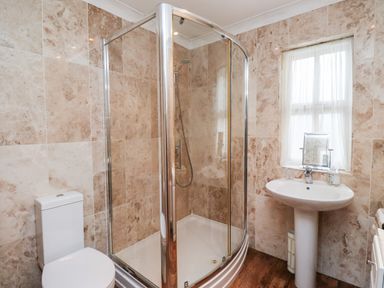A bathroom with a corner shower enclosure toilet and pedestal sink at Darling Cottage in Bamburgh