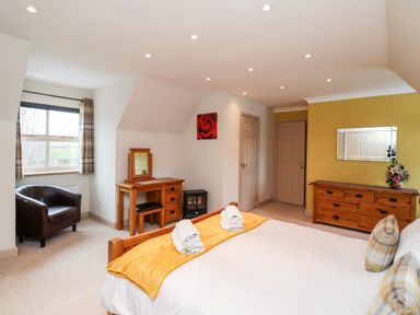 A bedroom with a bed towels and pillows a chair a dressing table and a dresser at Darling Cottage in Bamburgh