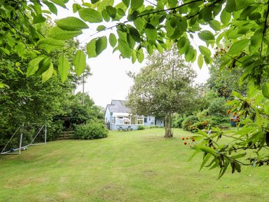 A garden with a grassy lawn a tree a soccer goal and a house in the background at Maesgwyn Bridell near Cardigan