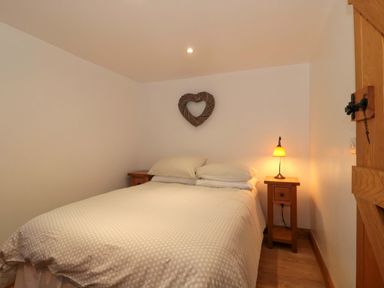 A bedroom with a bed and nightstand at Riverside Barn in Gilwern near Crickhowell and Abergavenny