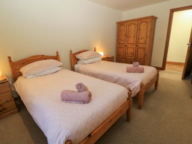 A bedroom with two single beds and wooden furniture at The Old Cart Shed in Winterborne Stickland