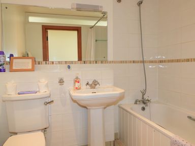 A bathroom with a toilet sink and bathtub with showerhead at The Old Cart Shed in Winterborne Stickland