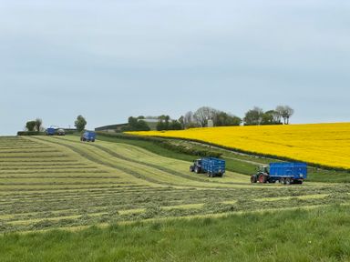 A landscape with tractors working in fields at The Old Cart Shed in Winterborne Stickland