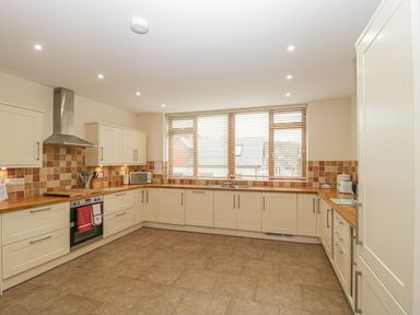 A kitchen with wooden countertops white cabinets a stainless steel oven and a large window at The Old Barn in Harman's Cross near Swanage