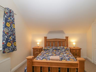A bedroom with a wooden bed and matching bedside tables with lamps at The Old Barn in Harman's Cross near Swanage