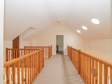 A hallway with wooden railings and three round ceiling lights at The Old Barn in Harman's Cross near Swanage