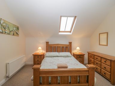 A bedroom with a wooden bed and matching nightstands under a skylight at The Old Barn in Harman's Cross near Swanage