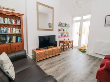 A living room with a bookshelf television small wooden table and chairs and a toy at The Robins in Filey