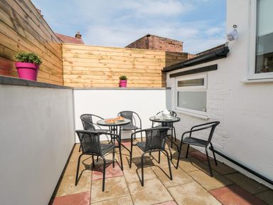 An outdoor patio with black metal chairs and tables with pastries and tea set at The Robins in Filey