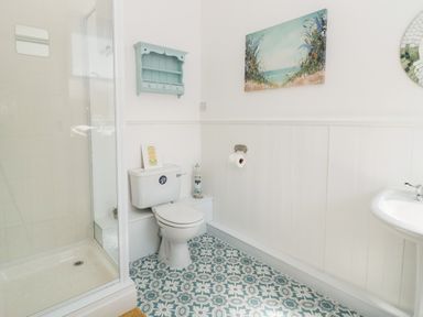 A bathroom with a toilet shower sink and patterned floor at The Robins in Filey