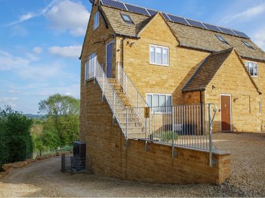 Stone house with external staircase and solar panels on the roof at Beautiful Cotswold View in Bourton-On-The-Water