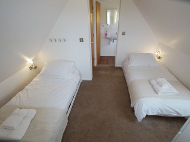 A bedroom with two single beds and an open door to a bathroom at Beautiful Cotswold View in Bourton-On-The-Water