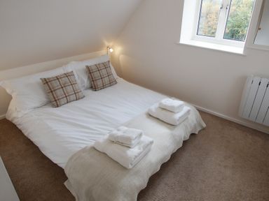 A bedroom with a double bed with white bedding and plaid pillows at Beautiful Cotswold View in Bourton-On-The-Water