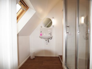 A bathroom with a wall-mounted sink and round mirror next to a glass shower enclosure at Beautiful Cotswold View in Bourton-On-The-Water