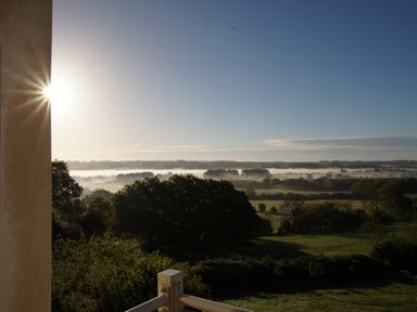 A sunrise view over fields and trees with mist in the distance at Beautiful Cotswold View in Bourton-On-The-Water