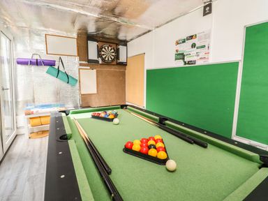 A game room with a pool table, cue sticks, a dartboard, and yoga mats at Beautiful Cotswold View in Bourton-On-The-Water